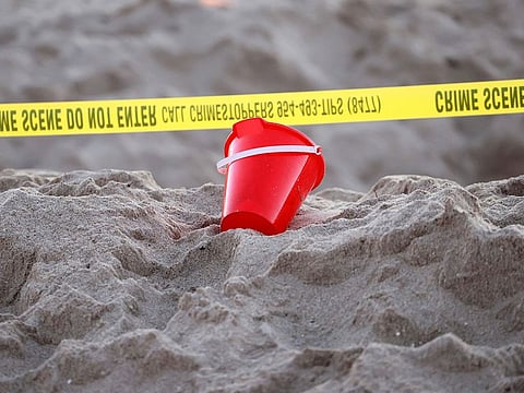 A pail rests next to caution tape on a beach in Lauderdale-by-the-Sea.