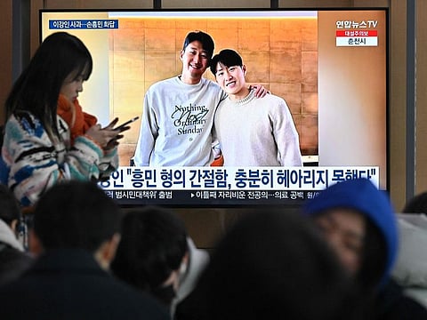 A woman walks past a television screen showing a news broadcast with a picture of Son Heung-min (left) and Lee Kang-in, at a railway station in Seoul on Wedensday.