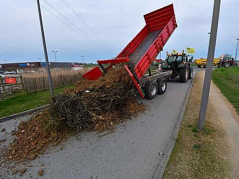 Farmers of the CR86 union (Coordination rurale 86) unload a skip of garbage and debris in front of a supermarket in Loudun, western France, on February 21, 2024. French farmers have resumed their actions ahead of President Emmanuel Macron's visit to a high-tension Salon de l'Agriculture (Agriculture Fair) on February 24, 2024.