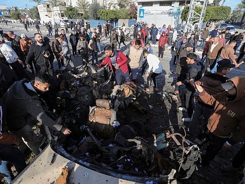 Palestinians inspect a car hit by an Israeli strike in Deir Al Balah, in the central Gaza Strip on February 21, 2024.