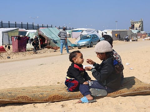 Displaced Palestinian girl, who fled her house due to Israeli strikes, feeds her brother at a tent camp, near the border with Egypt, in Rafah in the southern Gaza Strip, on February 25, 2024.
