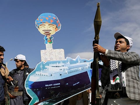 A Houthi follower holds a rocket launcher as others carry a cutout banner, portraying the Galaxy Leader cargo ship which was seized by Al Houthis, during a parade as part of a 'popular army' mobilization campaign by the movement, in Sana'a.