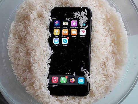 A view of a wet smartphone placed in a bowl of rice to dry.