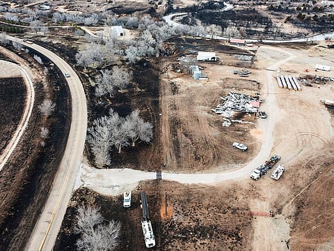 Electrical crews, bottom, replace burnt power poles near a destroyed residence, along the Canadian River in Canadian, Texas, Thursday, Feb. 29, 2024.