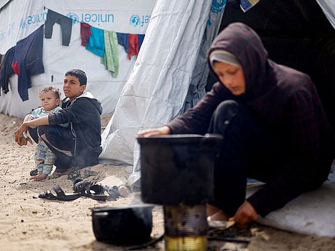 Displaced Palestinian children, who fled their houses due to Israeli strikes, sit at a tent camp, amid the ongoing Israeli bombing, in Rafah in the southern Gaza Strip