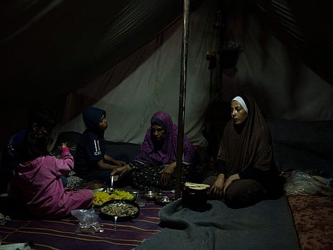 Randa Baker, right, and her family, who were displaced by the Israeli bombardment of the Gaza Strip, end their fast on the first day of Ramadan at a makeshift tent camp in the Muwasi area, southern Gaza, on March 11, 2024.