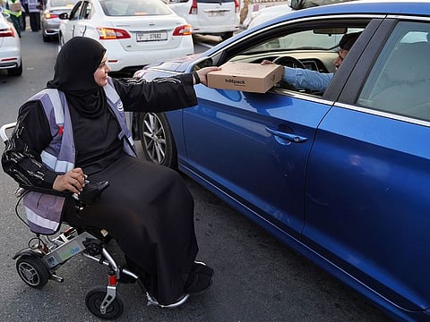 A Dubai Customs volunteer distributes meals at Iftar time in Dubai as part of the community Iftar initiative.
