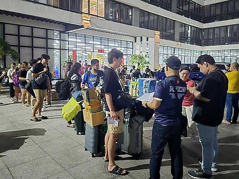 This undated handout photograph received from Philippines' Presidential Anti-Organized Crime Commission (PAOCC) on March 14, 2024 shows a police officer  (front, centre) talking to foreign nationals after a raid in a 25-acre complex of buildings in Bamban town of Tarlac province, north of Manila.