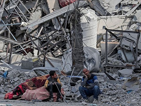 Displaced Palestinians sit with their belongings amid the rubble of houses destroyed by Israeli bombardment in Khan Yunis in Southern Gaza