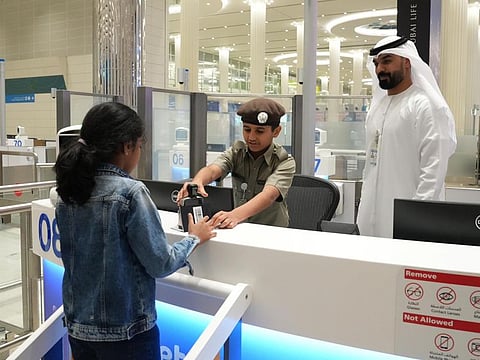 Omar Saood Al Malih stamps a young traveller's passport on Friday