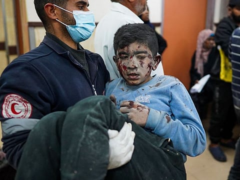 A medic carries a wounded Palestinian boy into the Al Aqsa Martyrs Hospital in Deir Al Balah on March 19, 2024, following Israeli bombardment in the Nuseirat refugee camp in the central Gaza Strip.