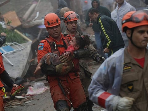 Rescue workers carry a girl who was rescued from her collapsed house after heavy rains in Petropolis, Rio de Janeiro state, Brazil, Saturday, March 23, 2024.