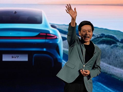 Xiaomi founder Lei Jun, waves after introducing the SU7, a sporty four-door sedan in Beijing.