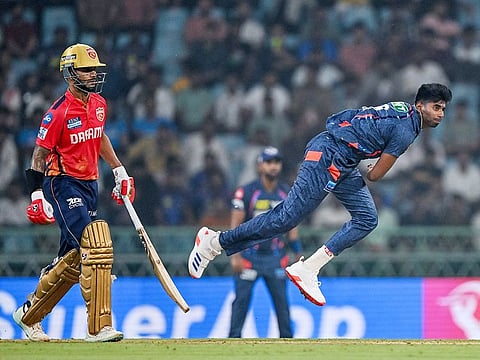 Lucknow Super Giants' Mayank Yadav bowls as Punjab Kings' captain Shikhar Dhawan (L) watches during the IPL 2024 match at the Ekana Cricket Stadium in Lucknow on March 30, 2024.