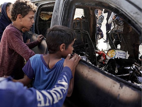 People gather around the carcass of a car used by US-based aid group World Central Kitchen, that was hit by an Israeli strike the previous day in Deir Al Balah in the central Gaza Strip on April 2, 2024.