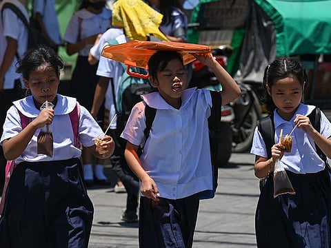 A student uses an envelop to protect herself from the sun during a hot day in Manila on April 2, 2024. More than a hundred schools in the Philippine capital shut their classrooms on April 2, as the tropical heat hit "danger" levels, education officials said.