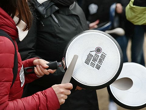 Protesters bang on pans, including one reading "behind the pans, our jobs!" as employees, managers and unionists of French cookware and small appliance manufacturer Tefal, owned by Groupe SEB, take part in a protest against a proposed law aimed at banning Per- and polyfluoroalkyl substances (PFAS) in France from 2026, which will affect almost 600 employees, at Place des Invalides in Paris on April 3, 2024.