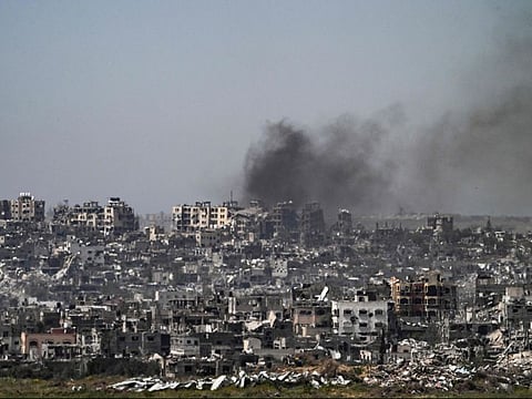 This picture taken from Israel's southern border with the Gaza Strip shows smoke billowing behind destroyed buildings due to Israeli strikes on the besieged Palestinian territory on April 2, 2024, amid the ongoing conflict between Israel and the militant group Hamas.