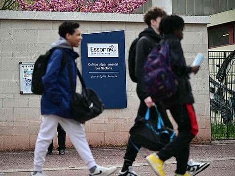 Middle schoolers walk by an indicative panel reading 'Departmental middle school - Les Sablons' at the entrance of the school Les Sablons in Viry-Chatillon on April 5, 2024, a day after a teenage boy was assaulted and rushed to the hospital.
