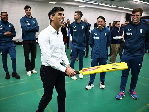 Britain's Prime Minister Rishi Sunak holds a cricket bat as he reacts while talking to England players during a visit to the Oval ground in London on Friday.