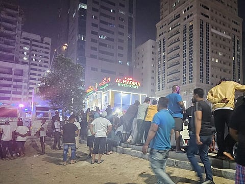 Residents seen on the road after a fire break out in a building in Sharjah