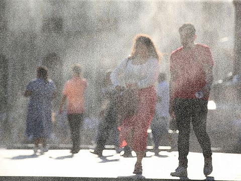 People walk as water is sprayed by a system to alleviate the high temperatures caused by a heat wave, at the Gerardo Barrios square, in San Salvador, El Salvador.
