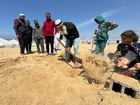 People bury the body of displaced Christian Palestinian Hany Dawood, who died of a kidney disease, at a Muslim graveyard, as his family was not able to receive his body and bury him at the Christian cemetery in Gaza City due to Israeli measures that ban the movement from the south of the Gaza Strip to its north, amid the ongoing conflict between Israel and the Palestinian Islamist group Hamas, in Rafah, in the southern Gaza Strip, April 7, 2024.