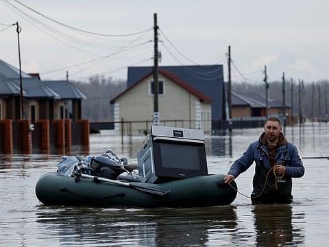A man tows an inflatable boat with his belongings along a flooded street in the settlement of Ivanovskoye, Orenburg region, Russia, April 10, 2024.