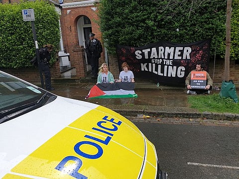 Police stand guard as Youth Demand activists sit in front of Britain's Labour leader Keir Starmer's house, demanding that Britain stop selling weapons to Israel amid high Palestinian child casualty rates in the Gaza conflict with Hamas militants, in London, Britain April 9, 2024 in this image obtained from social media.