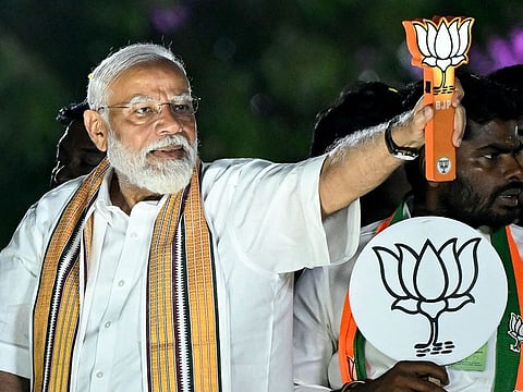 Modi holds the party symbol during a road show at an election campaign held ahead of the country's upcoming general elections, in Chennai on April 9, 2024.