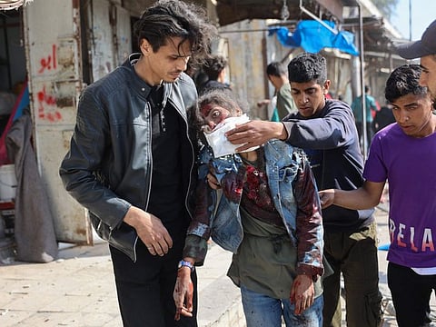 Palestinians help an injured girl following Israeli bombardment on the Firas market area in Gaza City on April 11, 2024.