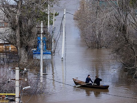 People row a boat through a flooded residential area in Orenburg, Russia, April 12, 2024.