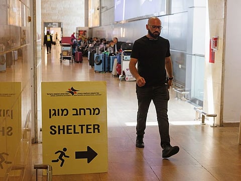 A passenger passes near a shelter room sign in the departure terminal of Ben Gurion airport on the day after a drone and missile attack from Iran, near Tel Aviv, Israel on Sunday, April 14, 2024.