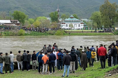 People gather along the Jhelum riverside as National Disaster Response Force (NDRF) personnel conduct a search and rescue operation after a boat with children overturned in Srinagar on April 15, 2024.