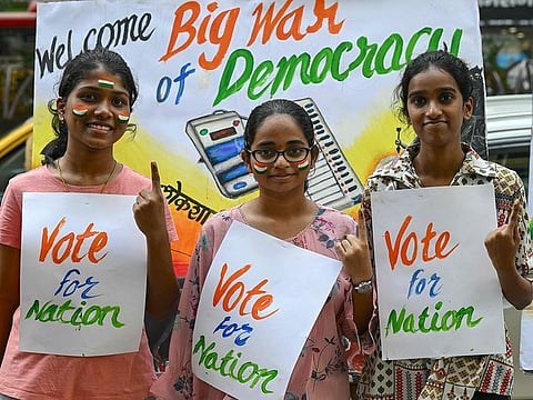 Art school students pose with posters illustrating India's elections, in Mumbai