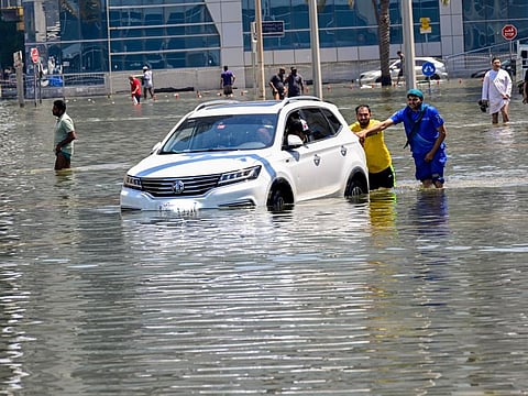 People push a vehicle through flooded Jamal abdul nasser street in Sharjah.. Photo: Virendra Saklani/Gulf News