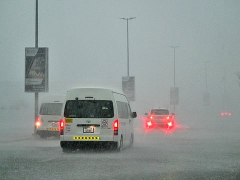 Vehicles drive on a flooded road during torrential rain in Dubai on April 16, 2024