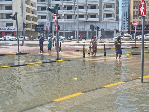 People wade through awater-logged part of Al Estiqlal Street in Sharjah.