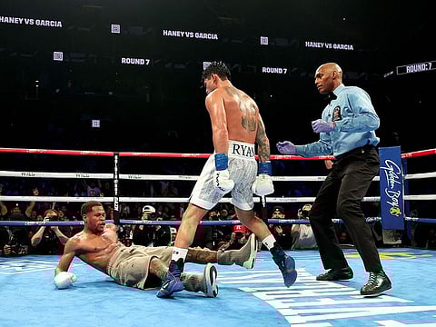 Ryan Garcia (white trunks) knocks down Devin Haney (gray trunks) during their WBC Super Lightweight title bout at Barclays Center in New York City.