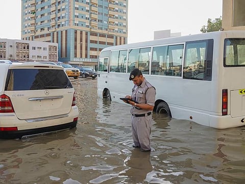An Ajman Police officer completes paperwork on behalf of a motorist to issue a loss and damage report for the vehicle after record rainfall in the UAE last week