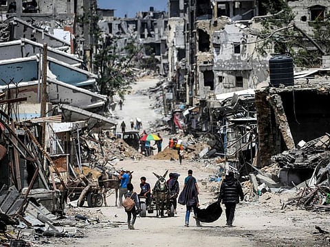 Boys ride a donkey-drawn cart moving past destroyed buildings in Khan Younis in the southern Gaza Strip on April 22, 2024.