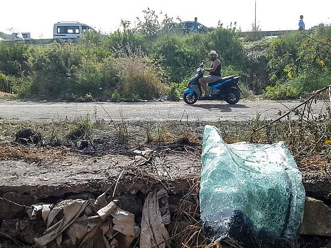 A motorist rides a motorcycle past the site of an Israeli strike on a vehicle in the Adloun plain area, between Lebanon's southern cities of Sidon and Tyre, on April 23, 2024.
