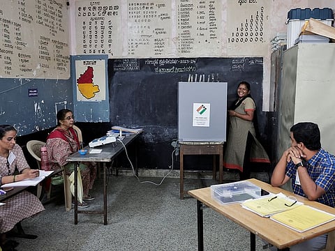 A woman smiles as she speaks with the election official while voting at a polling station, during the second phase of the general elections, at Bengaluru, in Karnataka, India April 26, 2024.