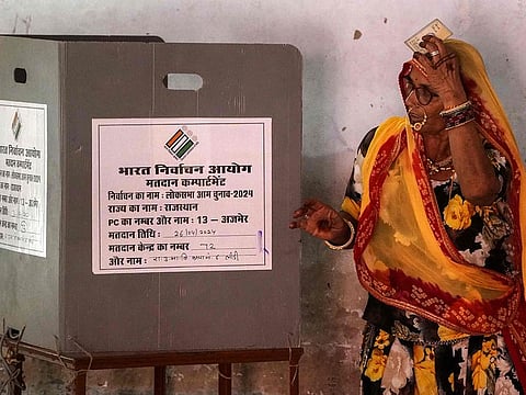 A woman voter prepares to cast her ballot at a polling station to cast their ballot in India