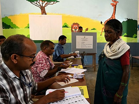 A voter from Kattunayakar tribe gets her documents verified before casting her vote at a polling station during the second phase of voting of India's general election in Wayanad district in Kerala on April 26, 2024.