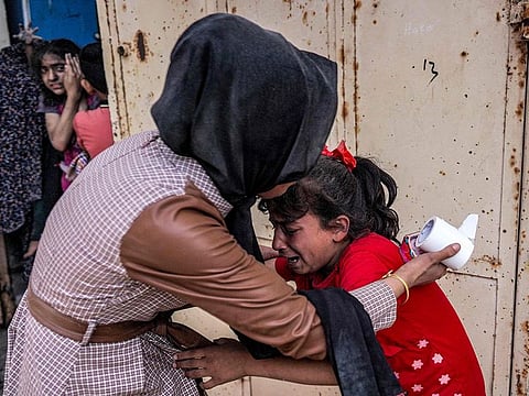 A woman consoles a shocked child reacting after Israeli bombardment in Nuseirat in the central Gaza Strip on April 29, 2024.