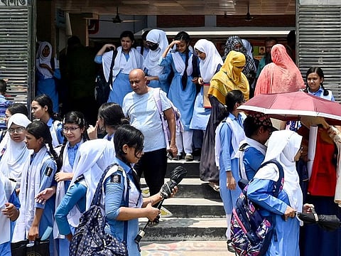 Students leaving their school compound carry umbrellas on a hot summer day in Dhaka