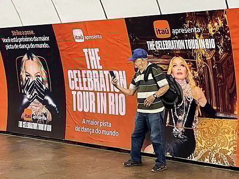 A man poses for a selfie with an ad for a mega-free concert by US pop star Madonna displayed at a metro station in the Copacabana neighbourhood of Rio de Janeiro, Brazil, on April 30, 2024. The singer will perform on May 4 on Rio de Janeiro's Copacabana beach to close her 'Celebration' tour.