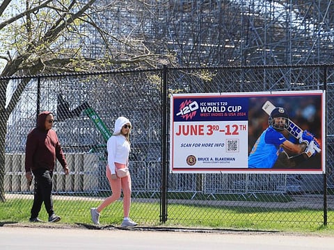 Pedestrians move past the construction site as work continues on the Nassau County International Cricket Stadium at Eisenhower Park in East Meadow, New York.