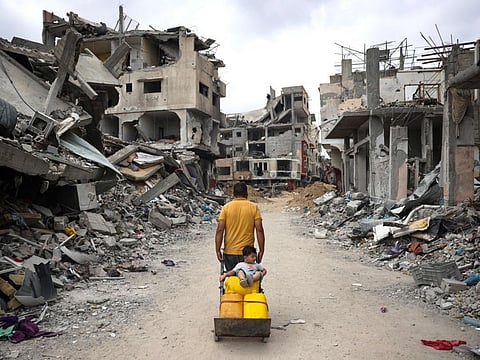 A Palestinian man pulls a cart on a road lined with destroyed buildings in Khan Younis in the southern Gaza Strip on May 2, 2024.
